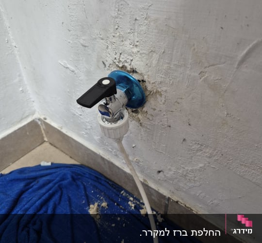 ברז מים מותקן בקיר עם צינור לבן